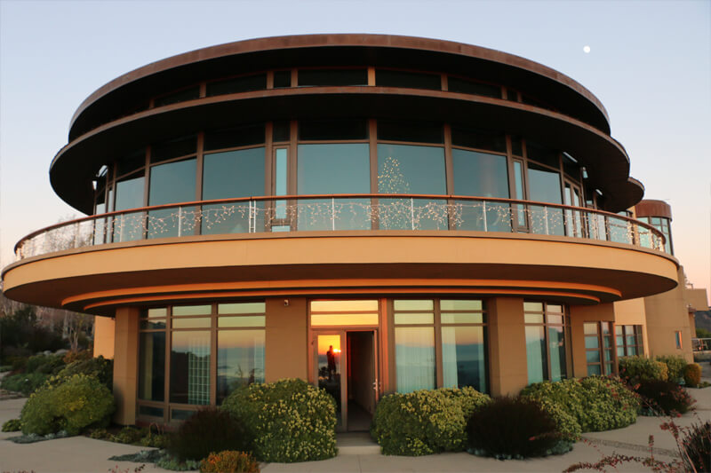 A completed two-story building with a curved balcony and large windows